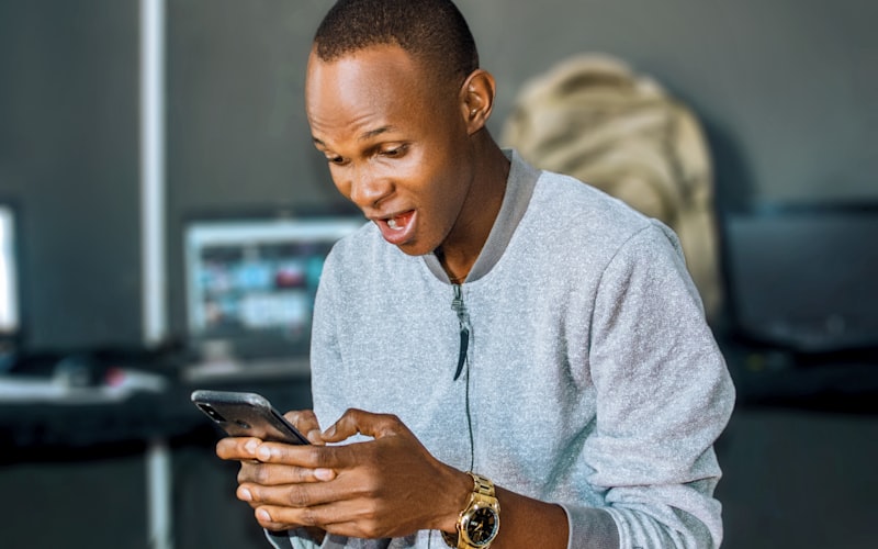 A man laughing while looking at his phone